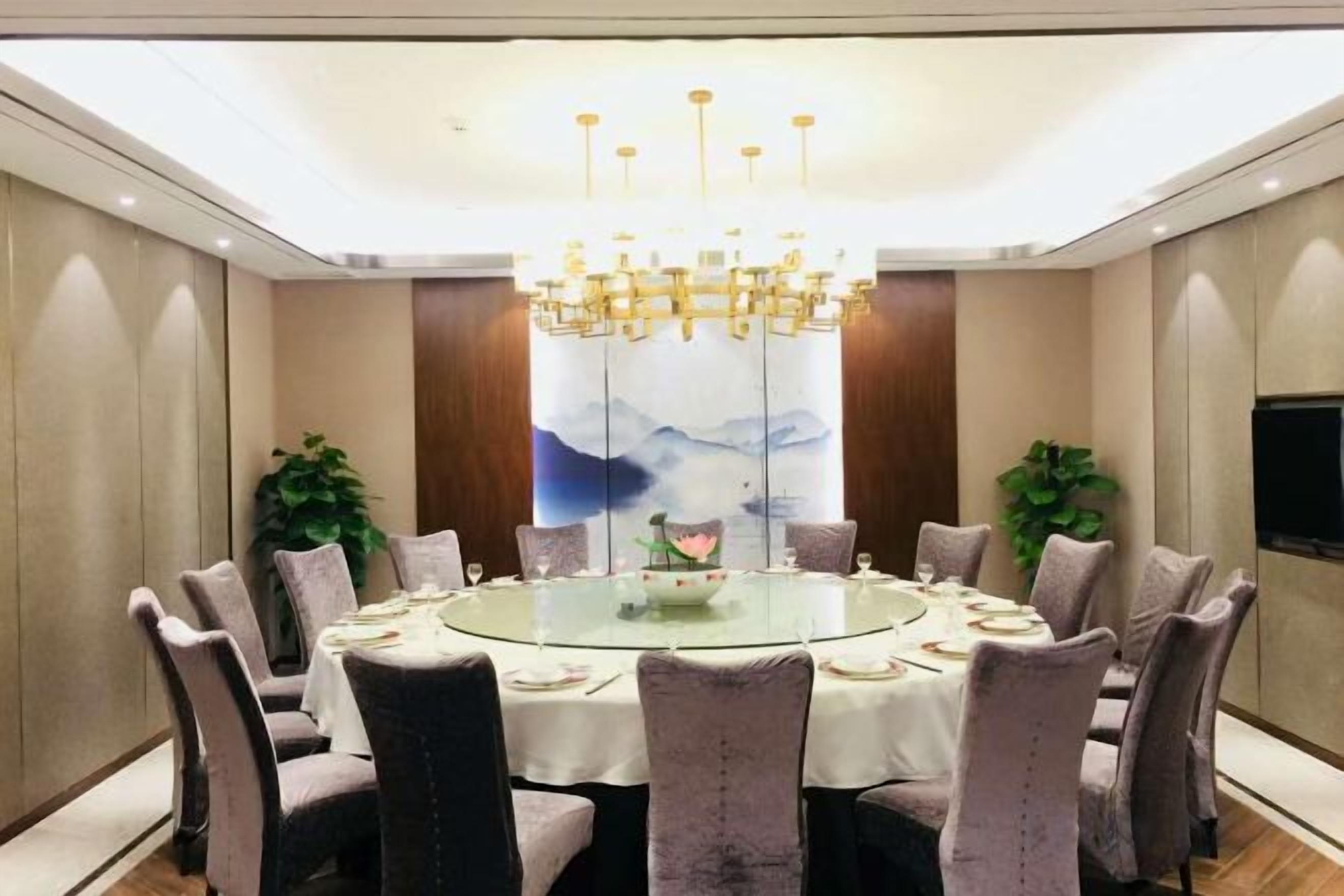 A conference room with a round table, chairs, and a chandelier.