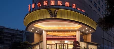 A hotel with a prominent entrance, a circular design, and a sign with Chinese characters.
