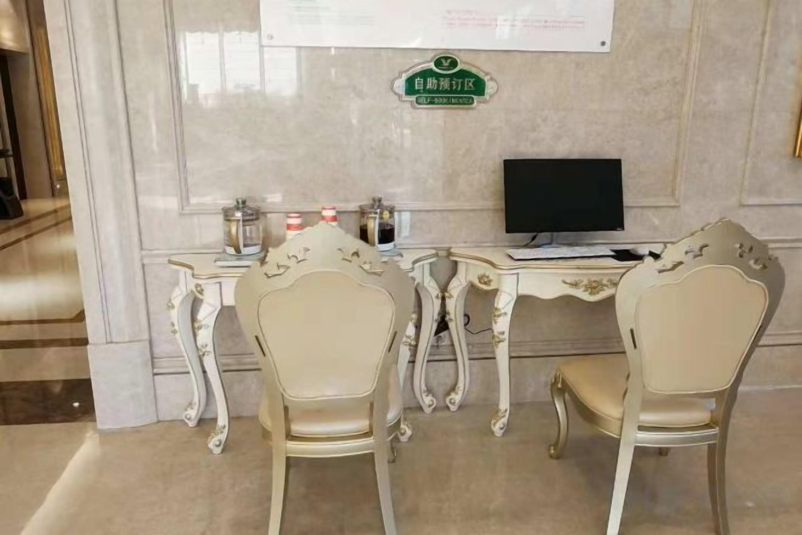 A room with two ornate chairs, a desk with a computer, and a sign on the wall.