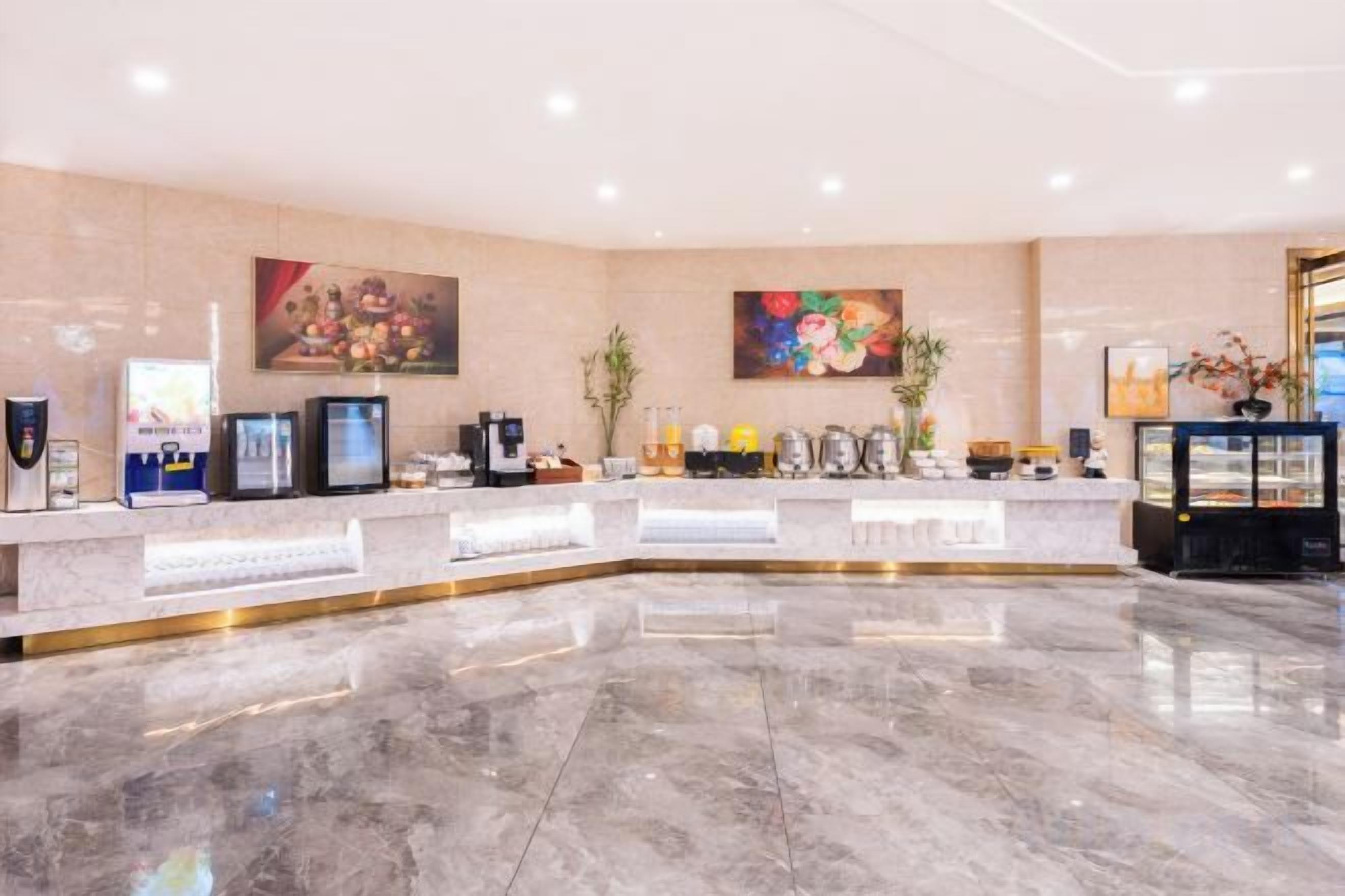 A hotel reception area with a marble floor, a reception desk, and two large paintings on the wall.