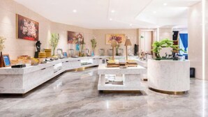 A modern hotel lobby with a marble reception desk, a seating area, and various decorative plants. - Vienna International Hotel (Wenzhou Avenue Railway Store) (Wenzhou)