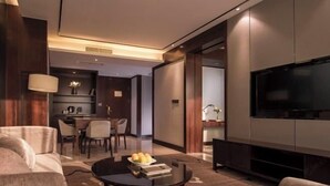 A modern living room with a sofa, a coffee table, a TV, and a dining area with chairs and a table. - Vienna International Hotel (Wenzhou Avenue Railway Store) (Wenzhou)