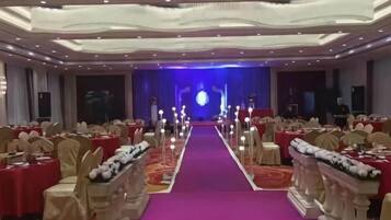 A banquet hall with a central aisle, rows of tables, and chairs.