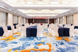 A conference room with rows of tables and chairs, a patterned carpet, and a stage at the front. - Vienna International Hotel (Wenzhou Avenue Railway Store) (Wenzhou)