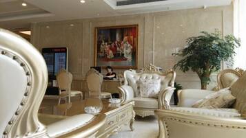 A luxurious lobby with ornate furniture, a large painting, and a digital information board.