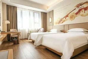 A hotel room with two beds, a desk, a chair, a lamp, and a large floral mural on the wall. - Vienna International Hotel (Wenzhou Avenue Railway Store) (Wenzhou)