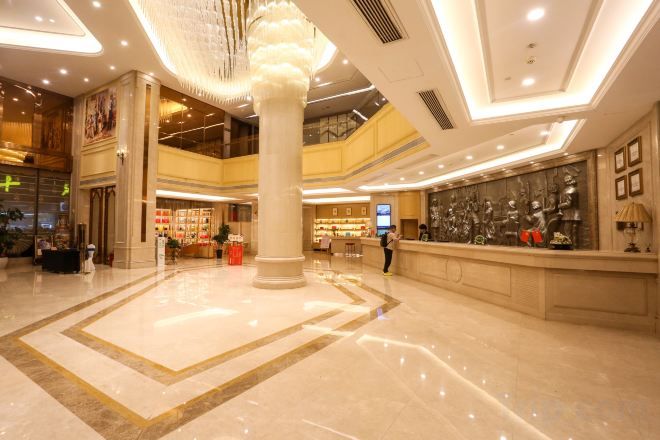 A spacious lobby with a central column, a reception desk, and a high ceiling with recessed lighting.