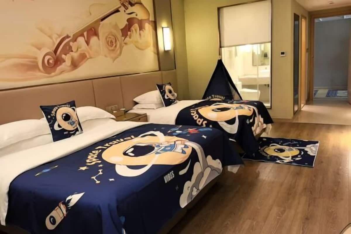 Habitación de hotel con dos camas, cada una cubierta con una colcha grande con motivos de personajes de dibujos animados.