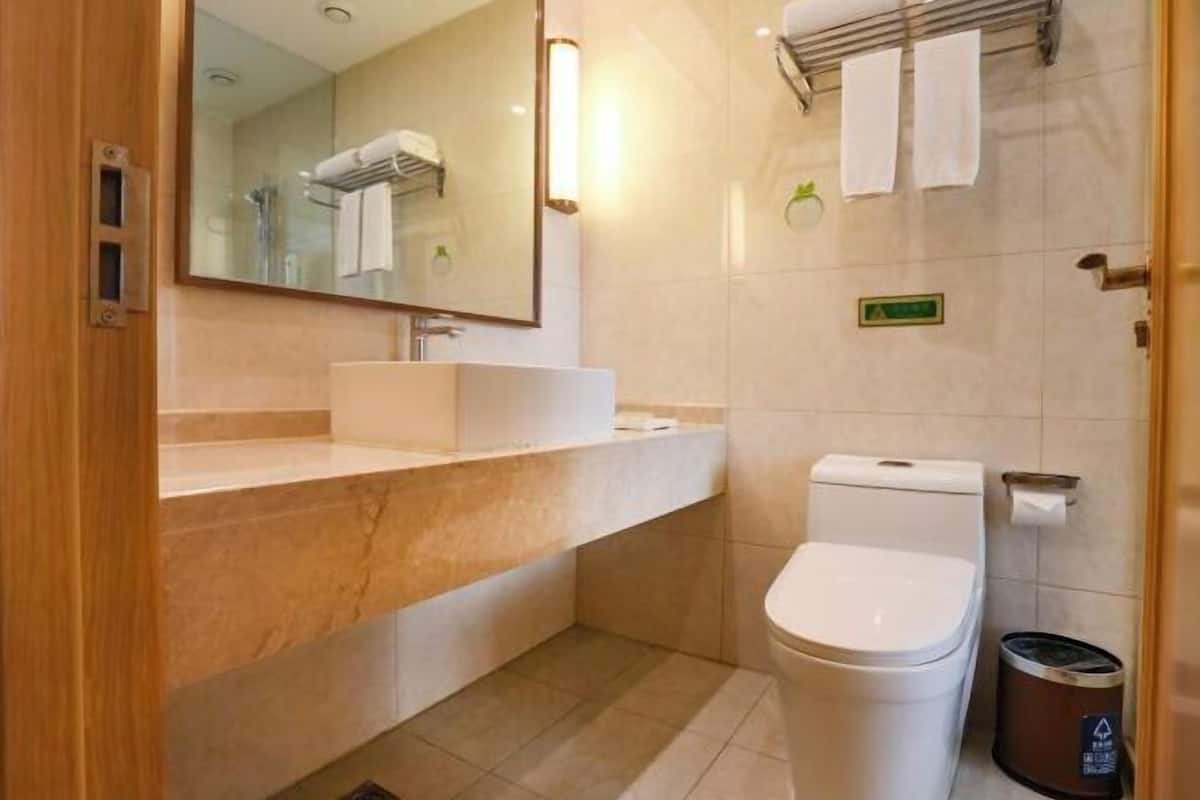 Un baño moderno con tocador de mármol, inodoro y zona de ducha.