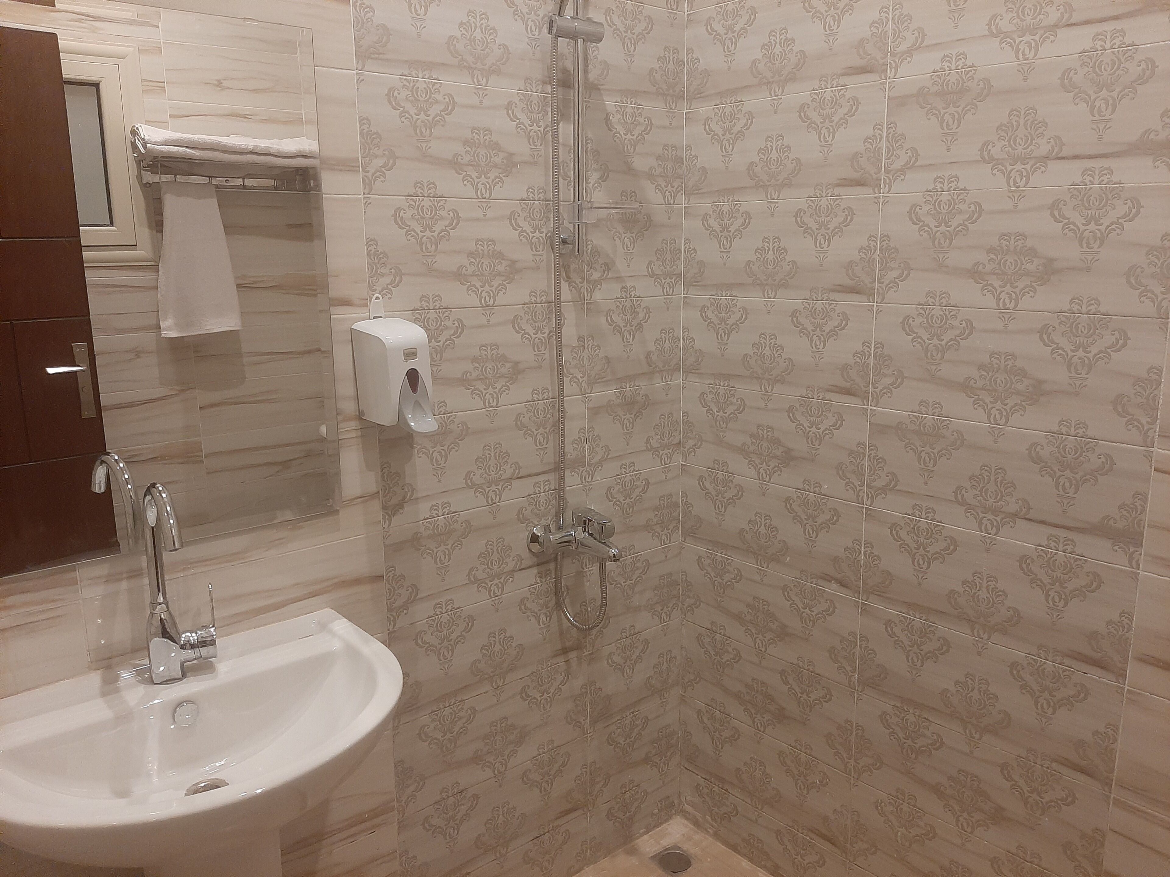 Un baño con lavamanos, espejo, ducha e inodoro.
