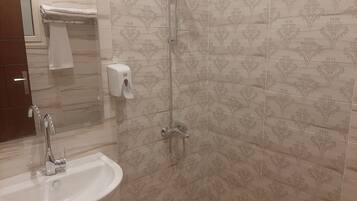 Un baño con lavamanos, espejo, ducha e inodoro.