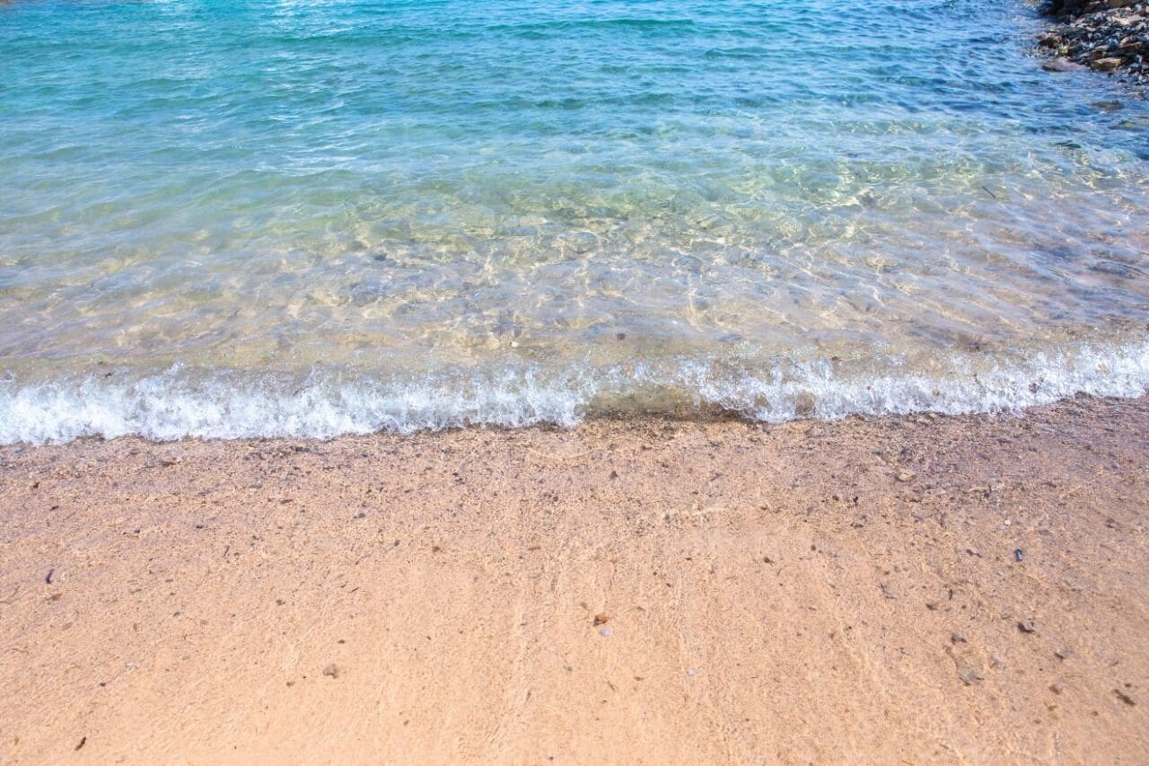 A sandy beach with clear water and gentle waves.