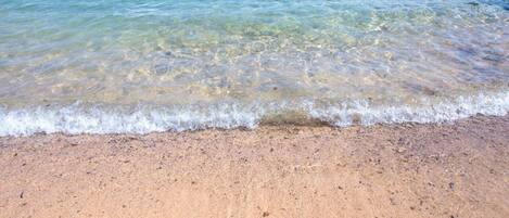 A sandy beach with clear water and gentle waves.
