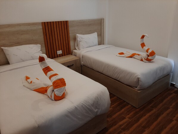 Two beds with white linens and orange and white striped towels arranged as if they are curling up. - La casa beach  (Hurghada)