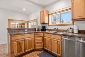 Una cocina moderna con armarios de madera, encimeras de granito y lavavajillas de acero inoxidable.