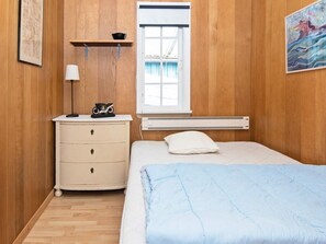Un dormitorio con cama, cómoda, ventana y radiador.