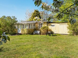 A house with a covered porch, a fenced yard, and a small table with chairs. - 4 Person Holiday Home in Odder (Odder)