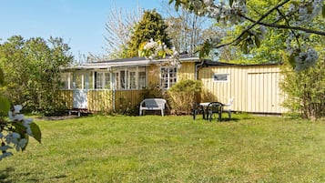 A house with a covered porch, a fenced yard, and a small table with chairs.