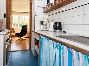 Una cocina con cafetera, hervidor y una silla.