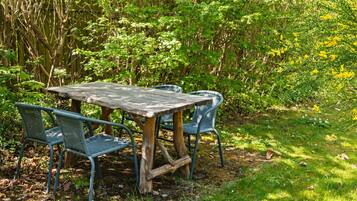 Een houten tuintafel met metalen stoelen in een tuin.