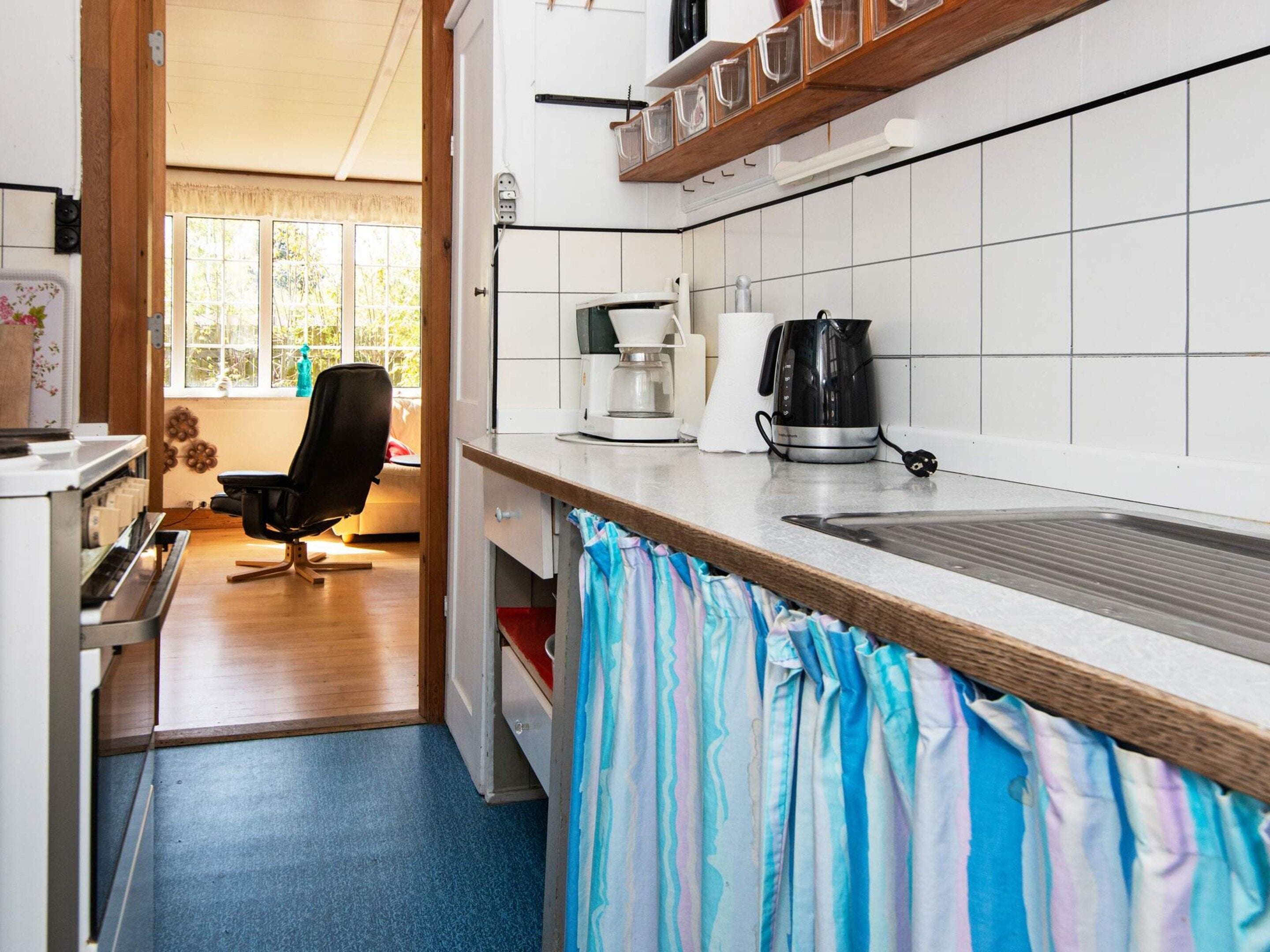 Una cocina con cafetera, hervidor y una silla.
