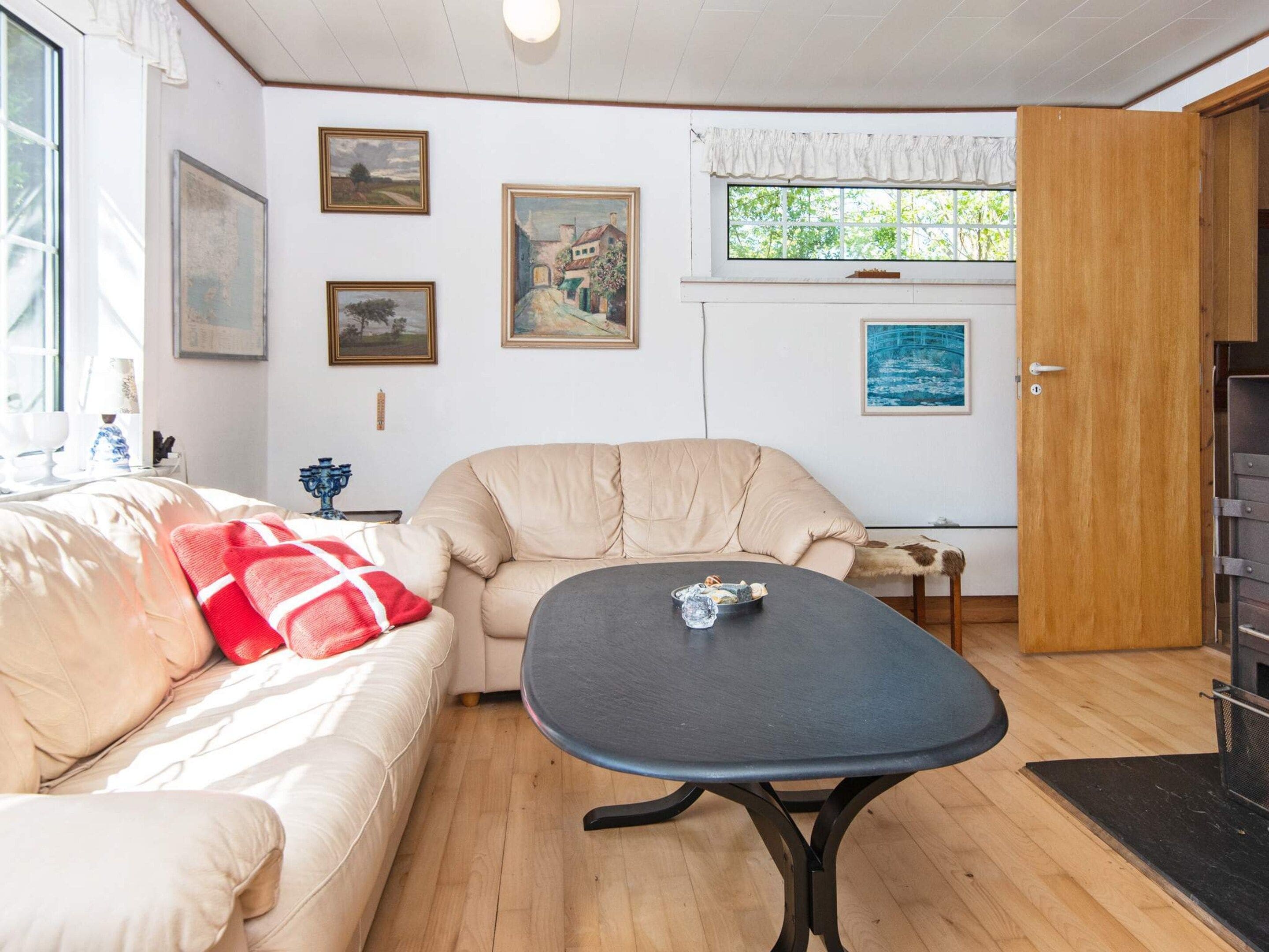 A cozy living room with a beige sofa, a round table, and a wooden floor.