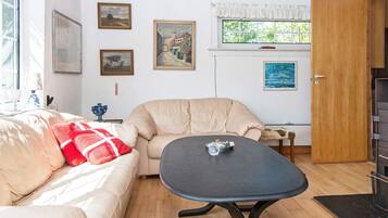 A cozy living room with a beige sofa, a round table, and a wooden floor.