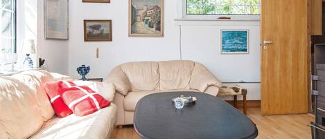 A cozy living room with a beige sofa, a round table, and a wooden floor.