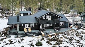 A two-story wooden cabin with a balcony, surrounded by snow-covered ground and trees. - 4 Star Holiday Home in Veggli (Rollag)