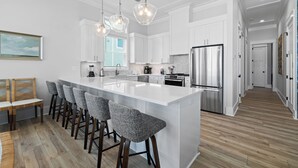 A modern kitchen with a large island, bar stools, and stainless steel appliances. - Money Beach: Private Pool, 7 Bedrooms, Sleeps 25! (Indian Pass)