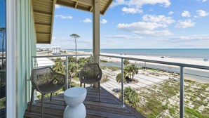 A balcony with two chairs and a table, overlooking a beach with a clear sky. - Money Beach: Private Pool, 7 Bedrooms, Sleeps 25! (Indian Pass)