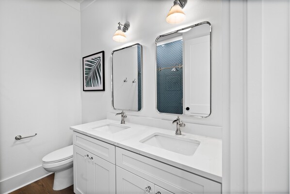 A modern bathroom with a white sink, two mirrors, and a toilet.