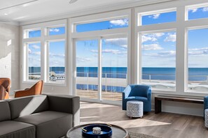 A spacious living room with large windows offering a view of the ocean and beach.