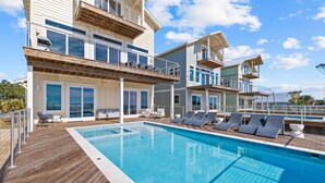A modern multi-story building with a swimming pool, outdoor seating, and balconies.