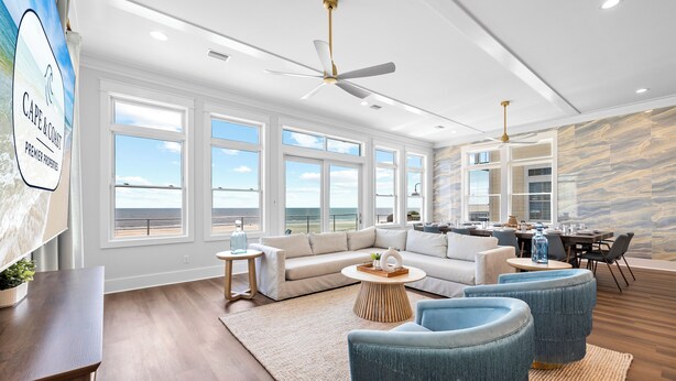 A spacious living room with a large window overlooking the ocean, a ceiling fan, and a dining area with a view. - Silver Strand: Large 7 BR Beachfront Home- Sleeps 24, Pet Friendly, Priv. Pool (Indian Pass)