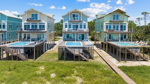 A beachfront property with multiple buildings, each featuring a pool and outdoor seating. - Silver Strand: Large 7 BR Beachfront Home- Sleeps 24, Pet Friendly, Priv. Pool (Indian Pass)