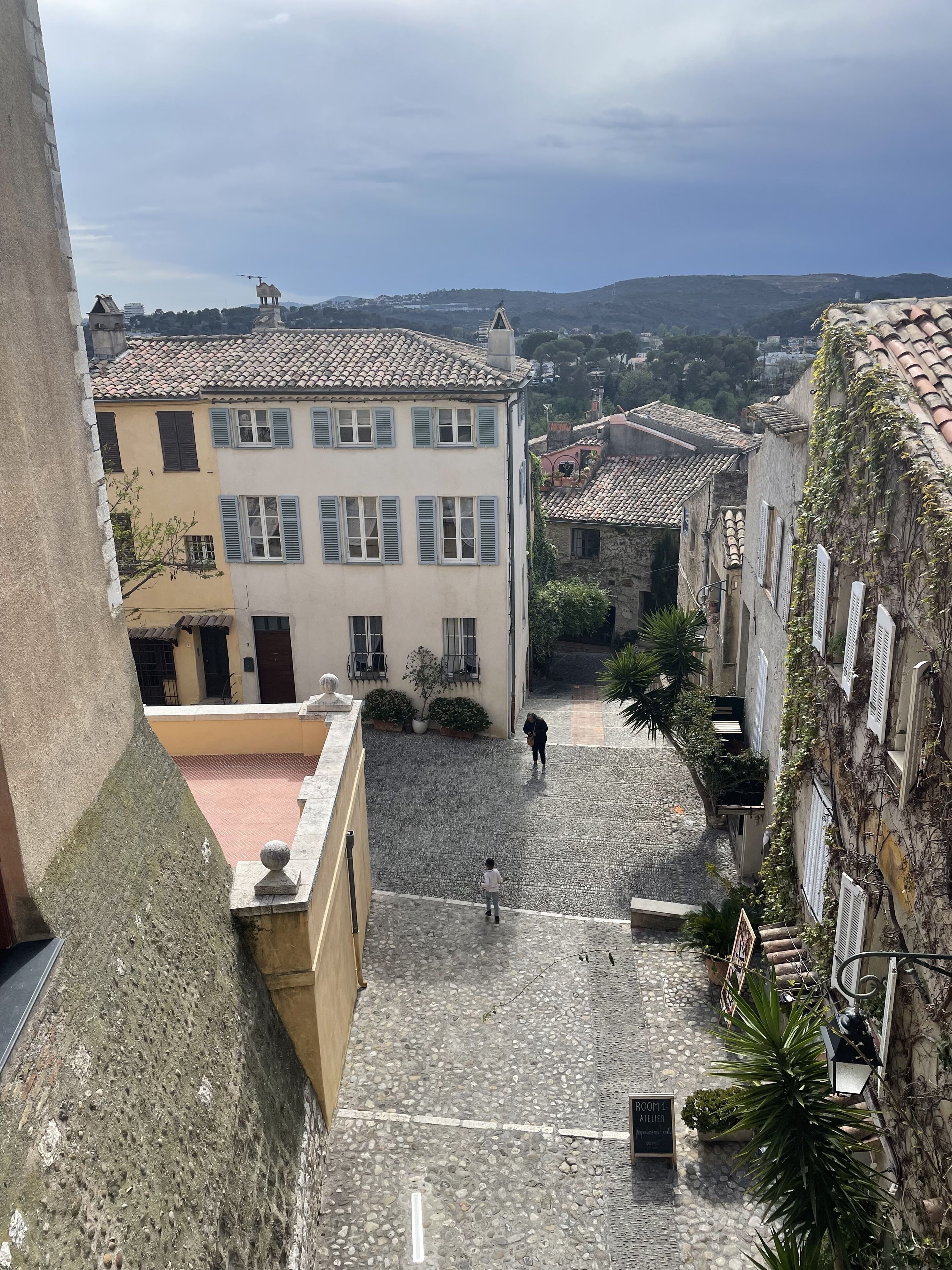 Un patio con suelo de adoquinado, edificios de arquitectura tradicional y una vista despejada del paisaje circundante.