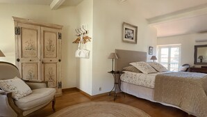 A bedroom with a bed, a chair, a lamp, and a wardrobe.