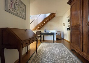 Stylish room with a high ceiling, wooden staircase, and a patterned rug.