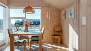 A wooden-paneled room with a dining table, chairs, a hanging light fixture, and a view of the outdoors. - 6 Person Holiday Home in Ringkobing-by Traum (Ringkobing)