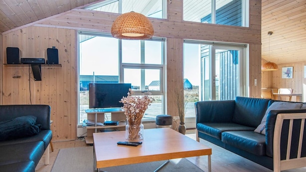 A modern living room with a wooden interior, a sofa, a coffee table, and a television. - 6 Person Holiday Home in Ringkobing-by Traum (Ringkobing)