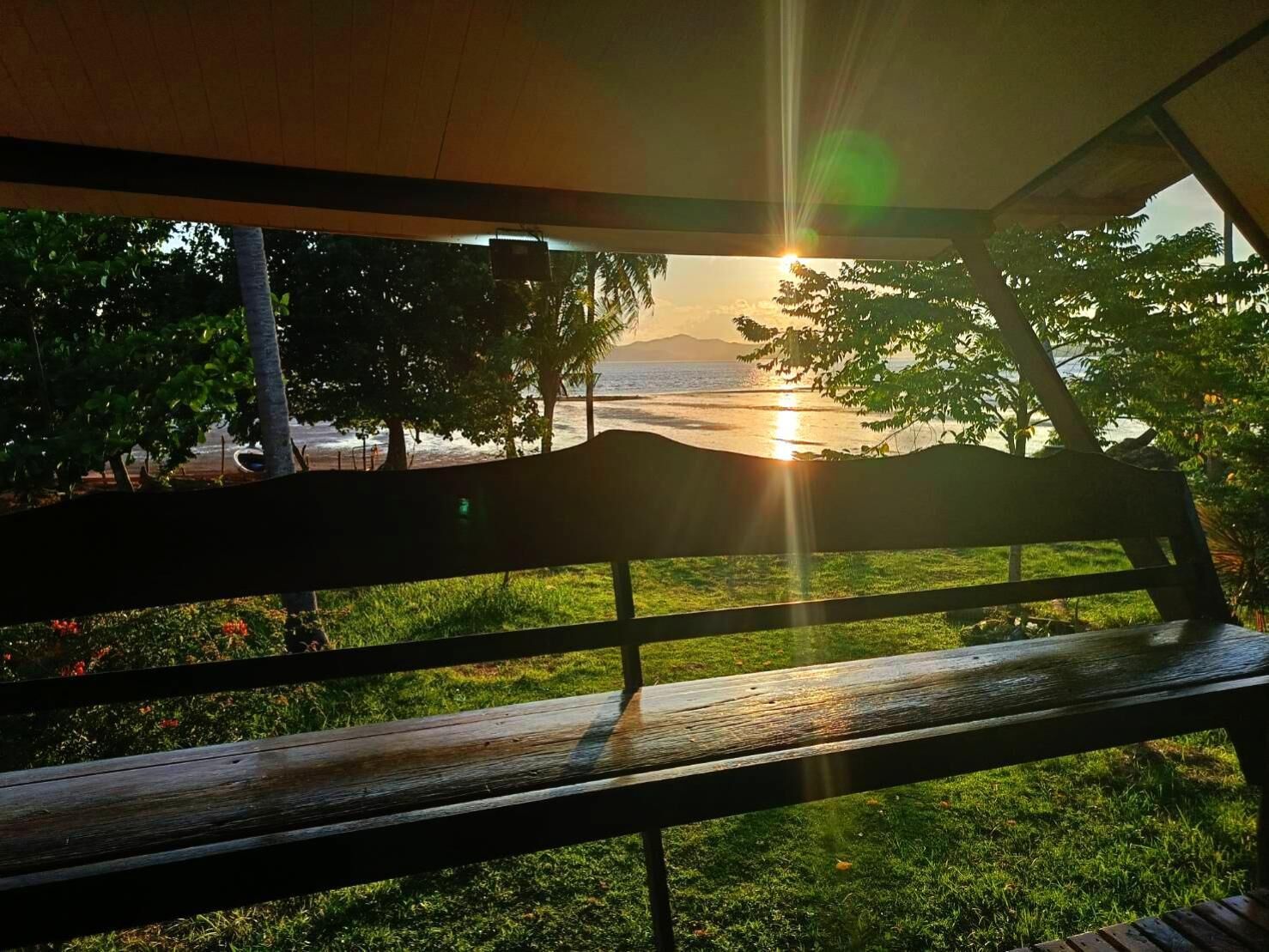 A wooden bench overlooking a beach with a sunset view.