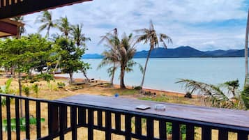A wooden deck with a view of a beach and palm trees.