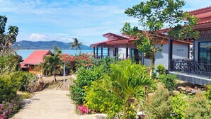 A coastal resort with multiple red-roofed villas, lush greenery, and a clear view of the sea and mountains in the background. - Leam Sai Bungalows Koh Yao Noi (Ko Yao)