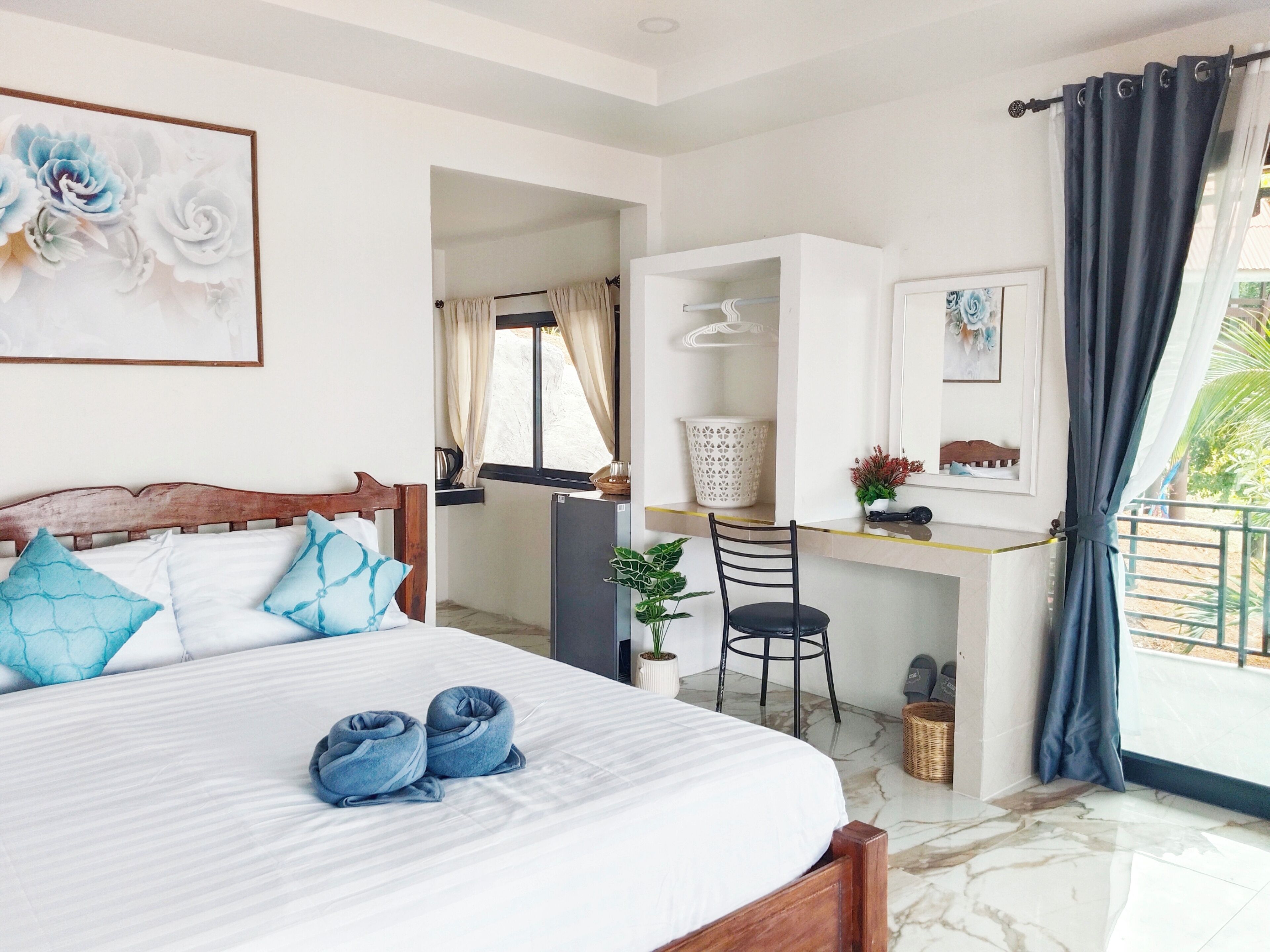 A bedroom with a bed, a desk, a chair, and a balcony.