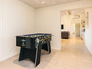 A room with a foosball table, a sofa, and a kitchen area. - 12 Person Holiday Home in Albaek (Aalbaek)