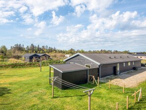 A large building with a flat roof, surrounded by a grassy field and trees. - 12 Person Holiday Home in Albaek (Aalbaek)