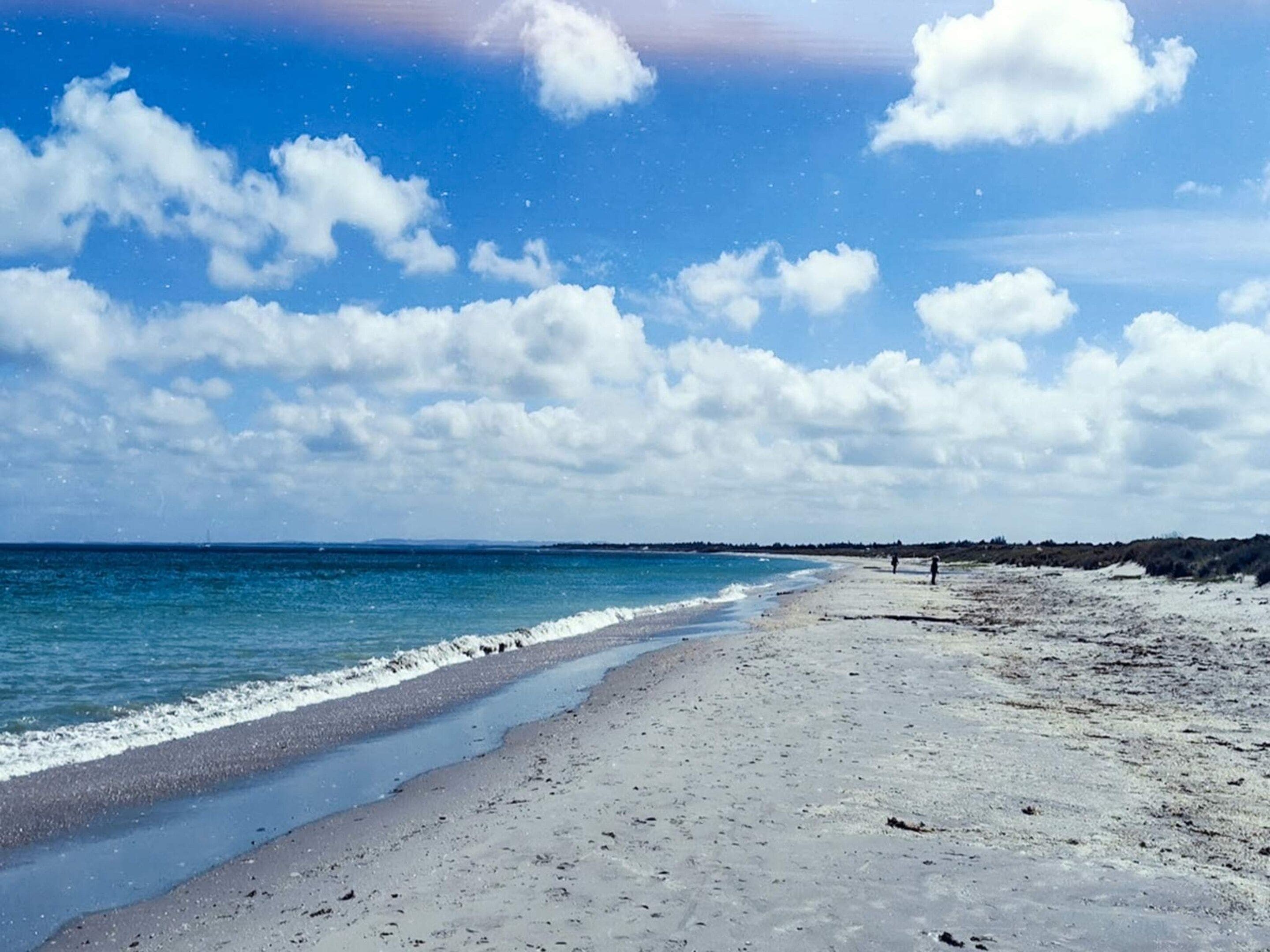 Una playa con cielo despejado y mar en calma.