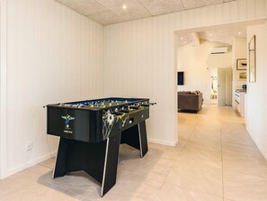 A modern room with a foosball table, a sofa, and a kitchen area. - 12 Person Holiday Home in Albaek (Aalbaek)
