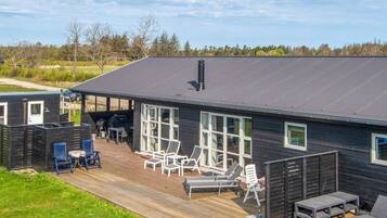 Et moderne hus med en terrasse, udendørs møbler og et stort vindue.